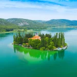 Visovac, samostan Visovac, rijeka Krka, Nacionalni park Krka, Visovačko jezero, franjevački samostan, kulturna baština Dalmacije, inkunabule, Ezopove basne 1487, paunovi Visovac, povijest Krke, Visovac, Visovac monastery, Krka River, Krka National Park, Visovac Lake, Franciscan monastery, Dalmatian heritage, incunabula, Aesop’s Fables 1487, peacocks Visovac, history of Krka